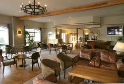 Modern hotel lounge with multiple seating areas, a bar, and a large chandelier.