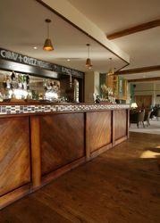 Interior view of a bar with a wooden counter and pendant lights