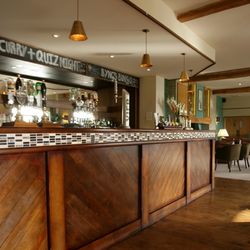 Wooden bar counter in a modern pub with bottles and glasses displayed behind