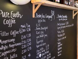 Chalkboard menu at a coffee shop with listings for coffee, tea, and chocolate drinks