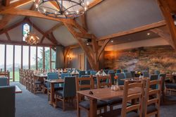 Interior of a spacious dining room with wooden beams, blue chairs, and a scenic mural on the wall.