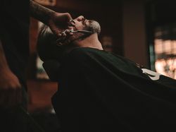 Man having his beard trimmed with scissors at a barbershop