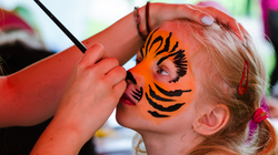 Child getting face painted like a tiger
