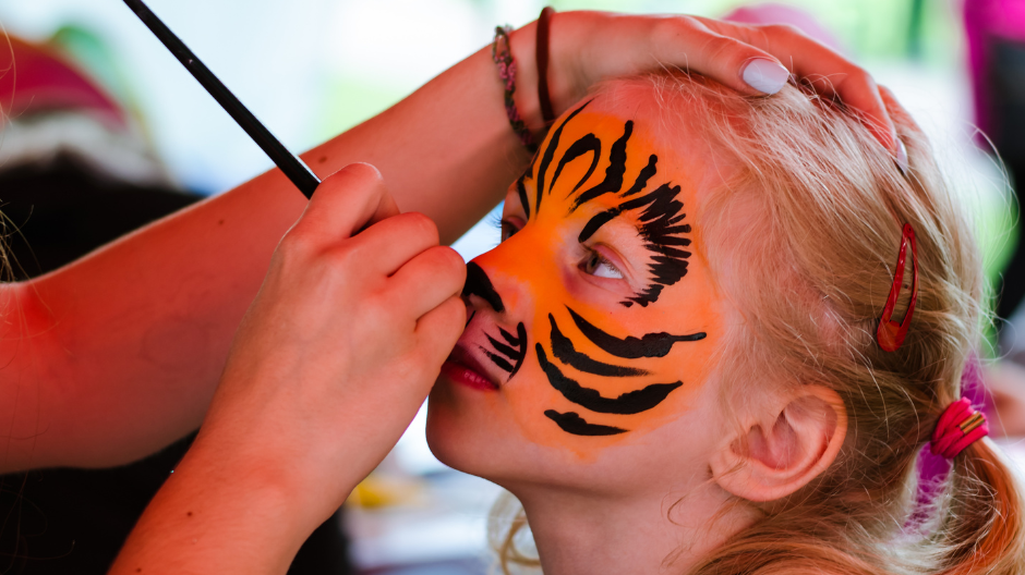 Child getting face painted like a tiger