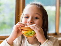 Young girl eating a sandwich indoors
