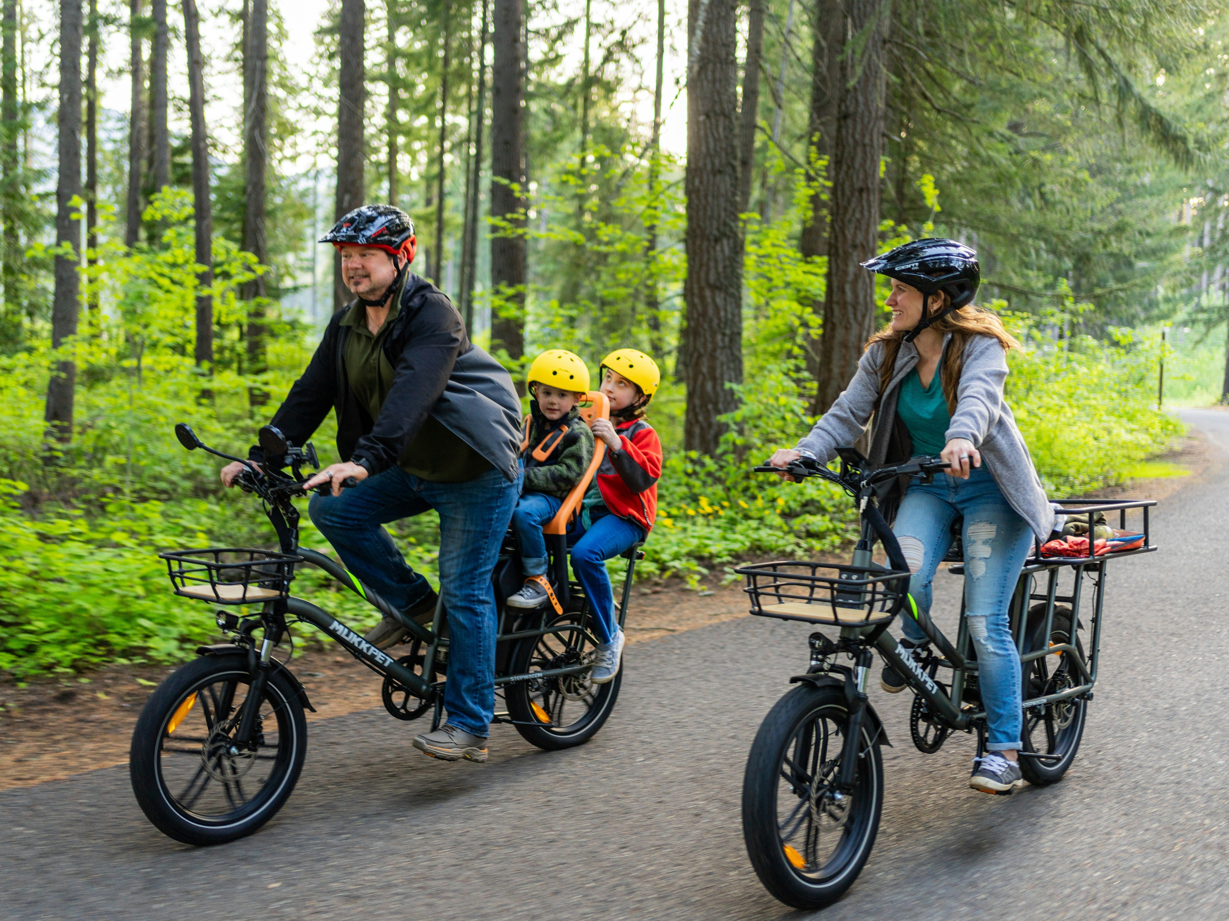 Family riding electric bikes together on a forested path