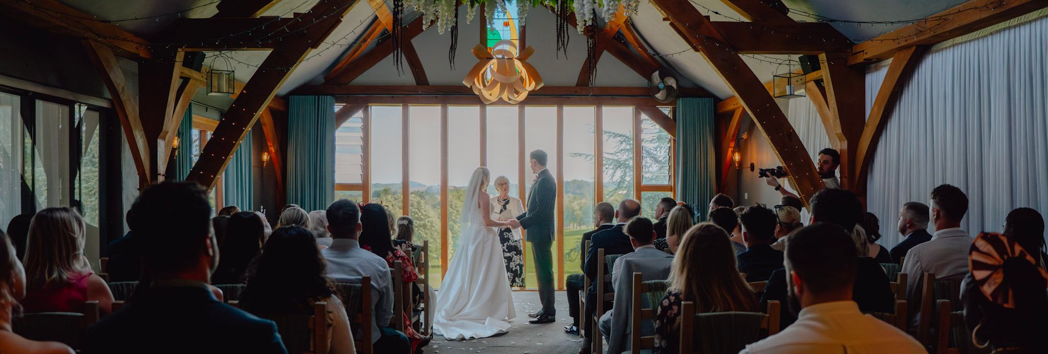Bride and groom standing at the altar during an indoor wedding ceremony with guests seated on both sides