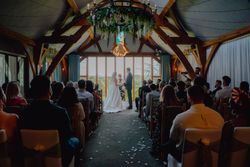 Bride and groom standing at the altar during an indoor wedding ceremony with guests seated on both sides