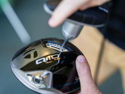 Person adjusting a golf club head with a tool