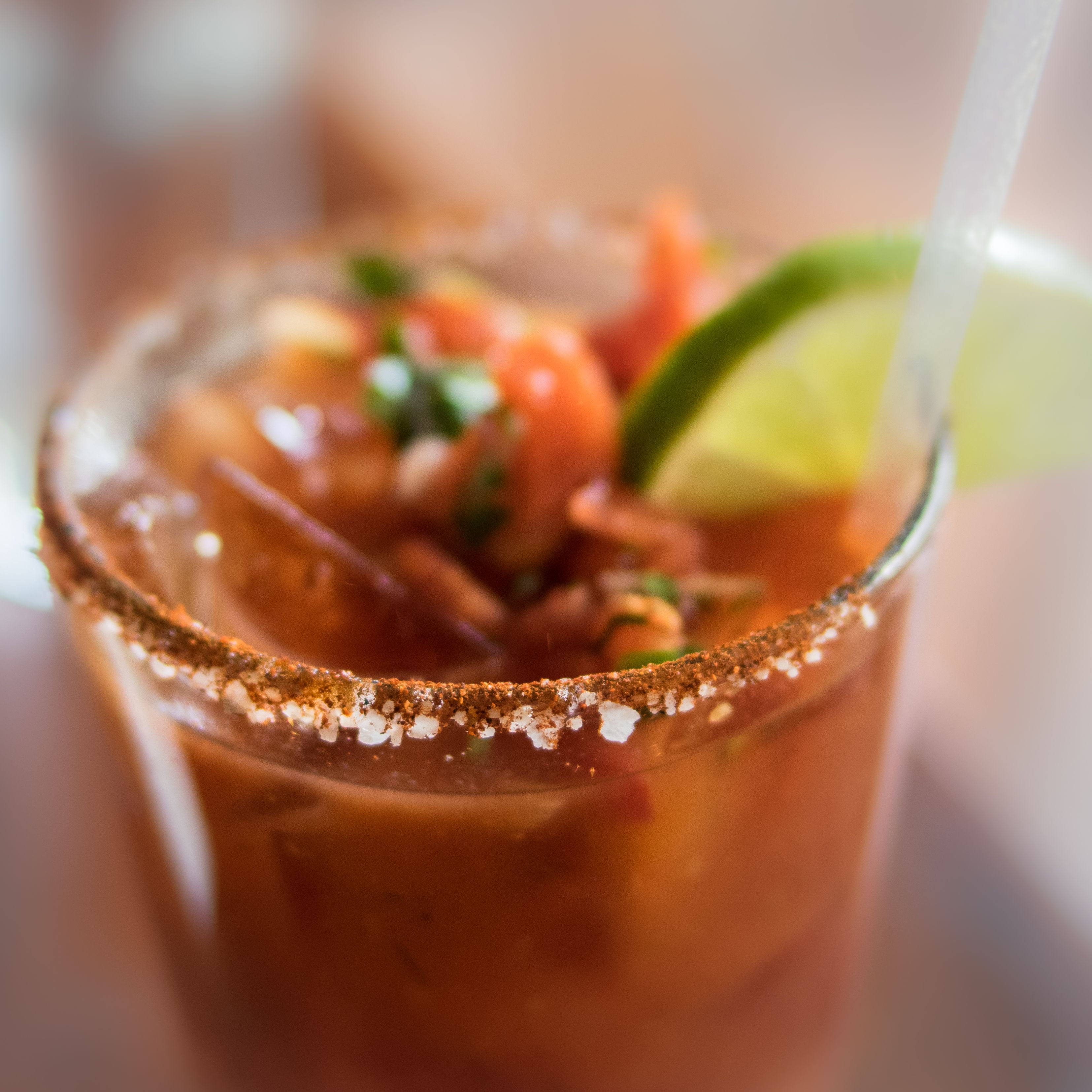 Close-up of a Bloody Mary cocktail garnished with lime and spices on the rim
