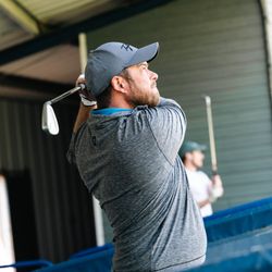 Man swinging a golf club at an indoor driving range