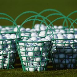 Green baskets filled with white golf balls on grass
