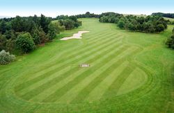 Aerial view of a golf course fairway with sand bunkers and tree-lined edges.