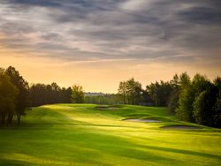Golf course at sunset with sand bunkers and trees in the background