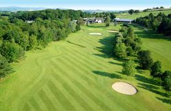 Aerial view of a golf course with sand bunkers and green fairways surrounded by trees.