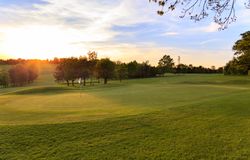 A golf course at sunset with the flagstick in the green