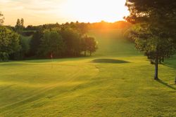 Golf course at sunset with a flag on the green