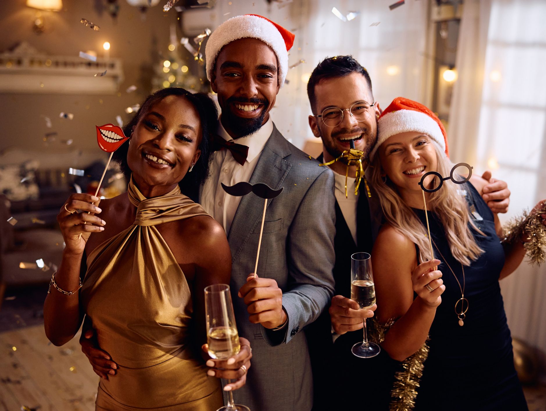 4 Fiends at a christmas party with prosecco, Santa hats and funny props