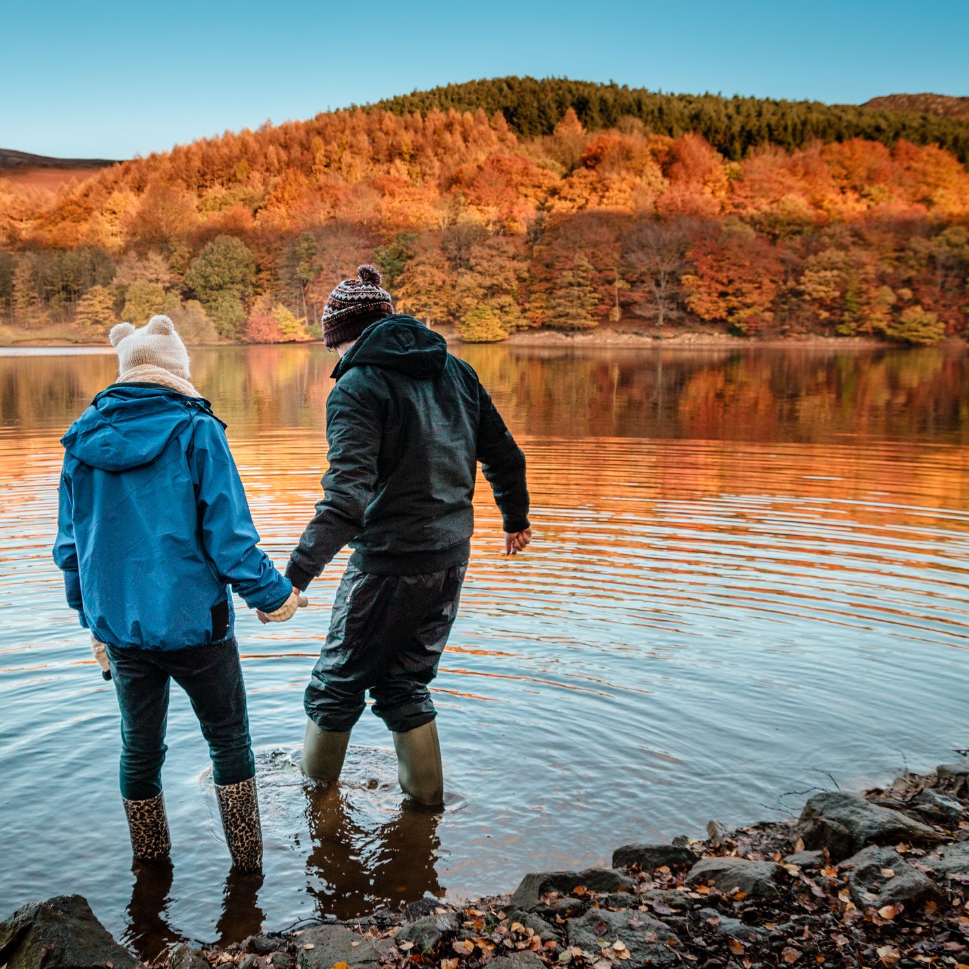 Autumn hills with a couple paddling in a lake with wellies on
