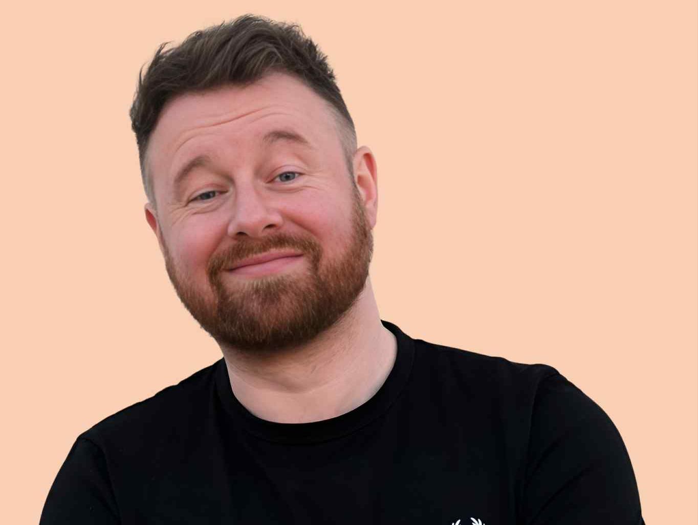 Smiling man with beard wearing a black t-shirt and crossing his arms