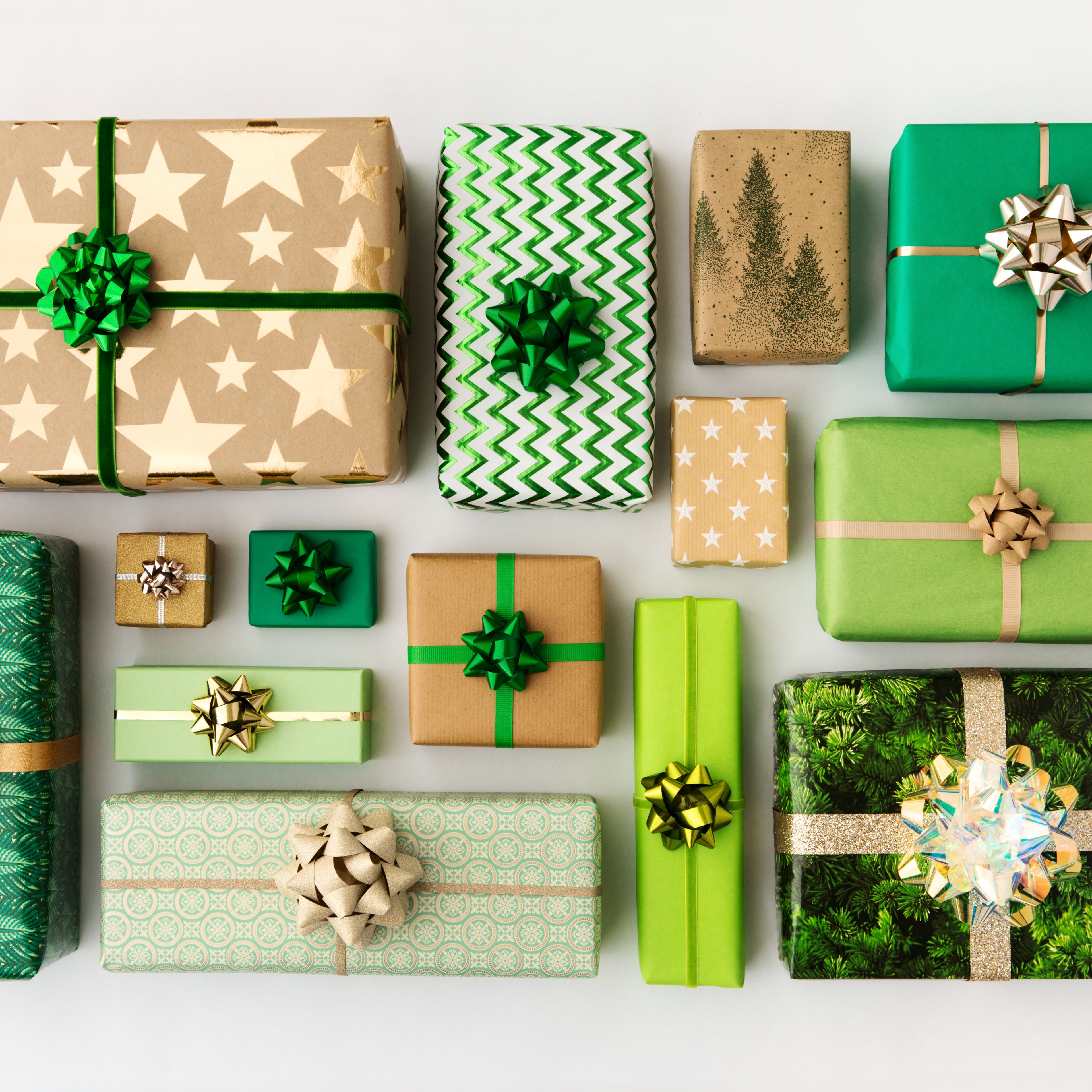 Assorted green and gold wrapped gifts with decorative bows arranged on a white background.