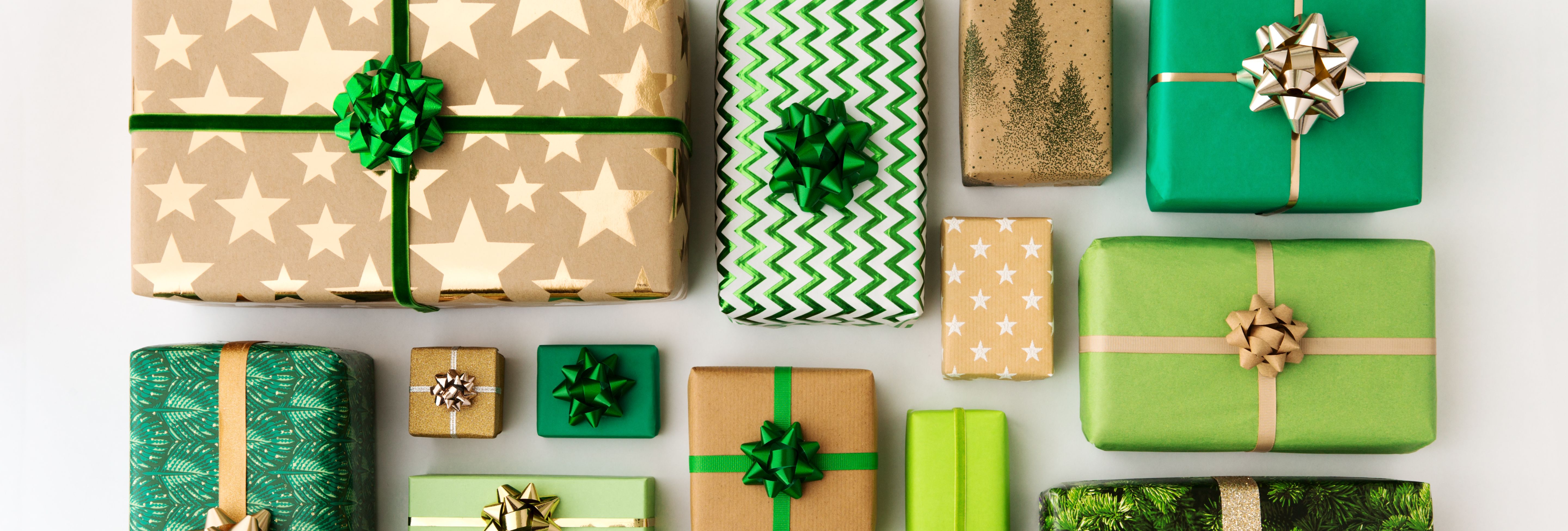 Assorted green and gold wrapped gifts with decorative bows arranged on a white background.