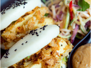 Fried chicken bao buns with black sesame seeds, served with salad and dipping sauce