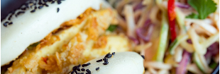 Fried chicken bao buns with black sesame seeds, served with salad and dipping sauce