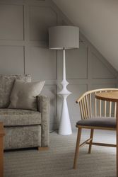 Modern living room corner with grey sofa, white floor lamp, and wooden chair