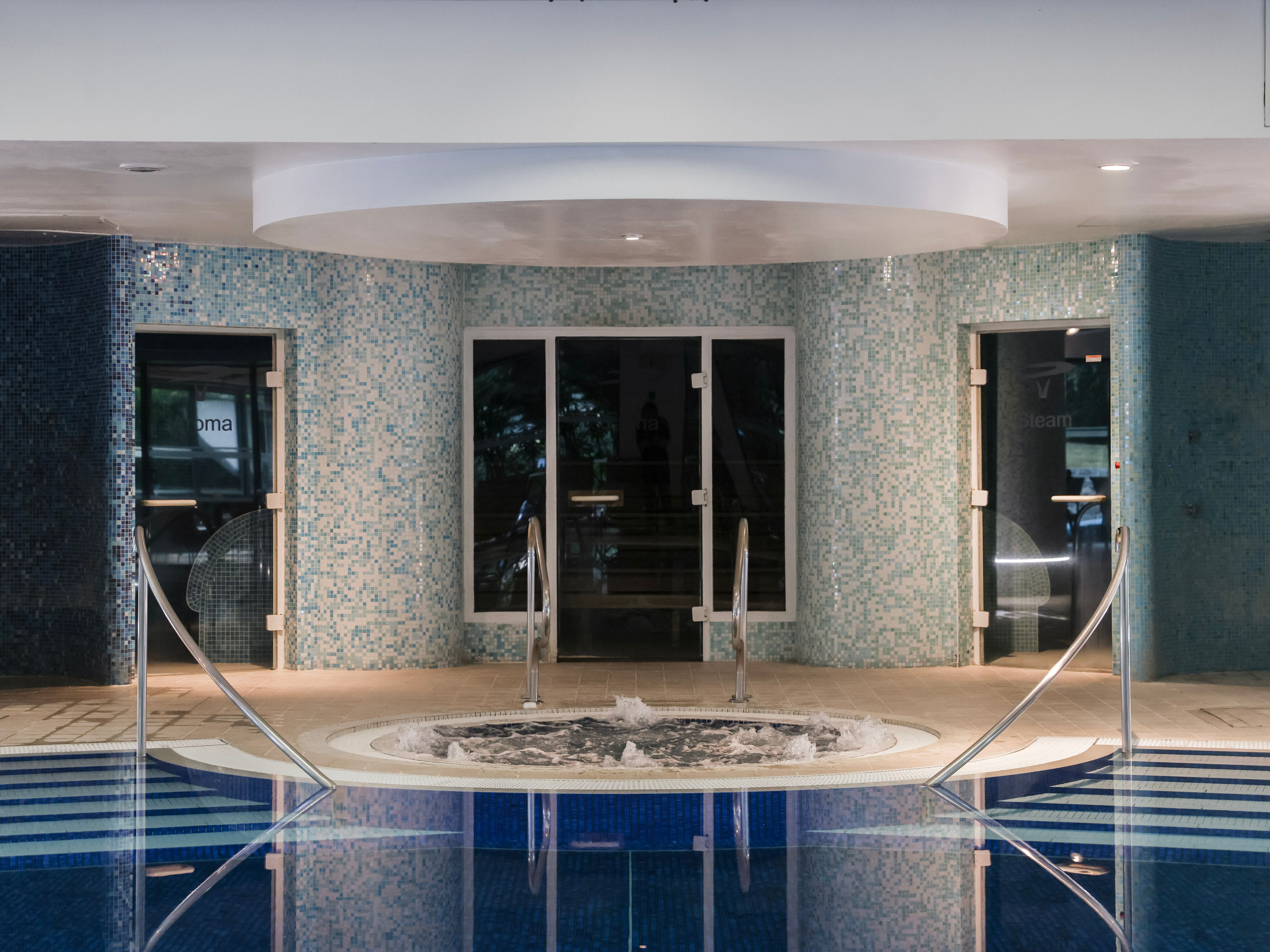 Indoor spa area with round jacuzzi and blue mosaic tiles