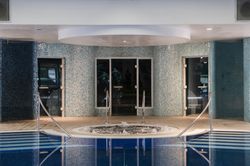 Indoor spa area with round jacuzzi and blue mosaic tiles