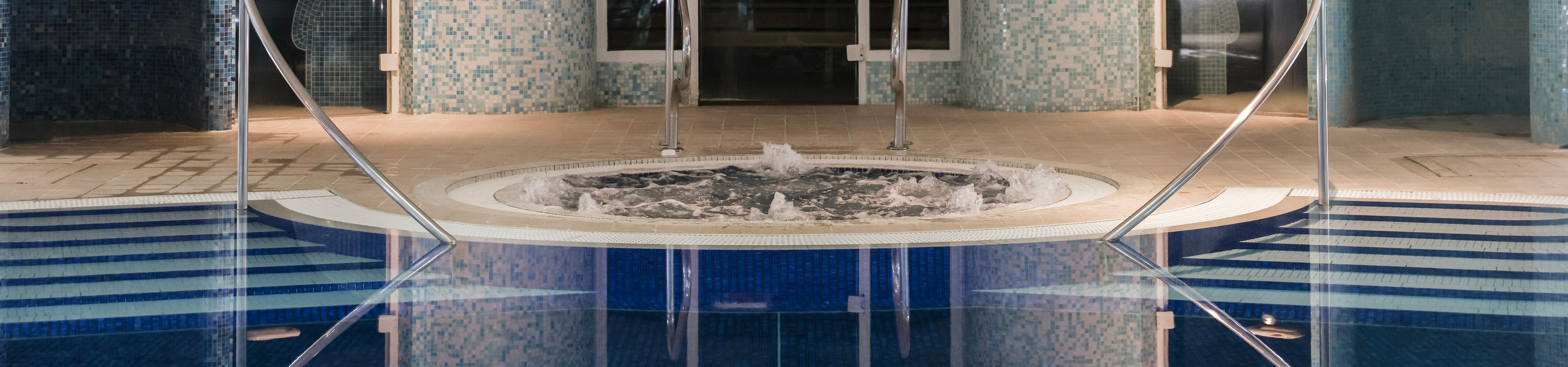 Indoor spa area with round jacuzzi and blue mosaic tiles