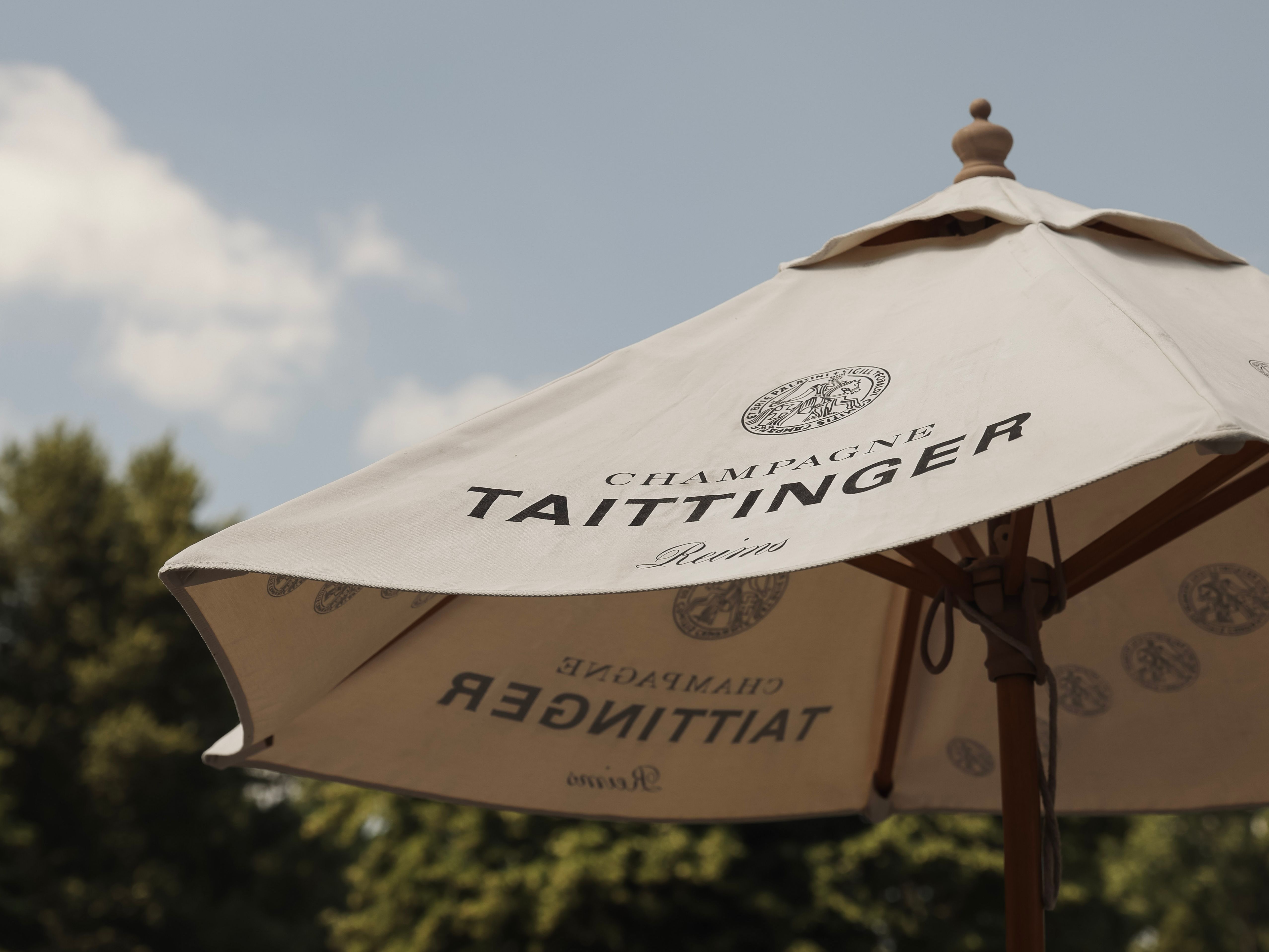Outdoor Taittinger champagne umbrella on a sunny day with trees in the background