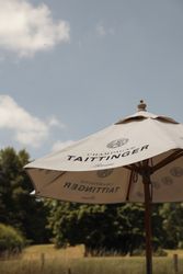Outdoor Taittinger champagne umbrella on a sunny day with trees in the background