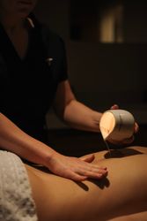 A person pouring massage oil onto someone's back during a spa treatment.