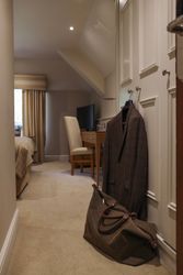 A cozy hotel room with a suit hanging on the door and a travel bag on the floor.