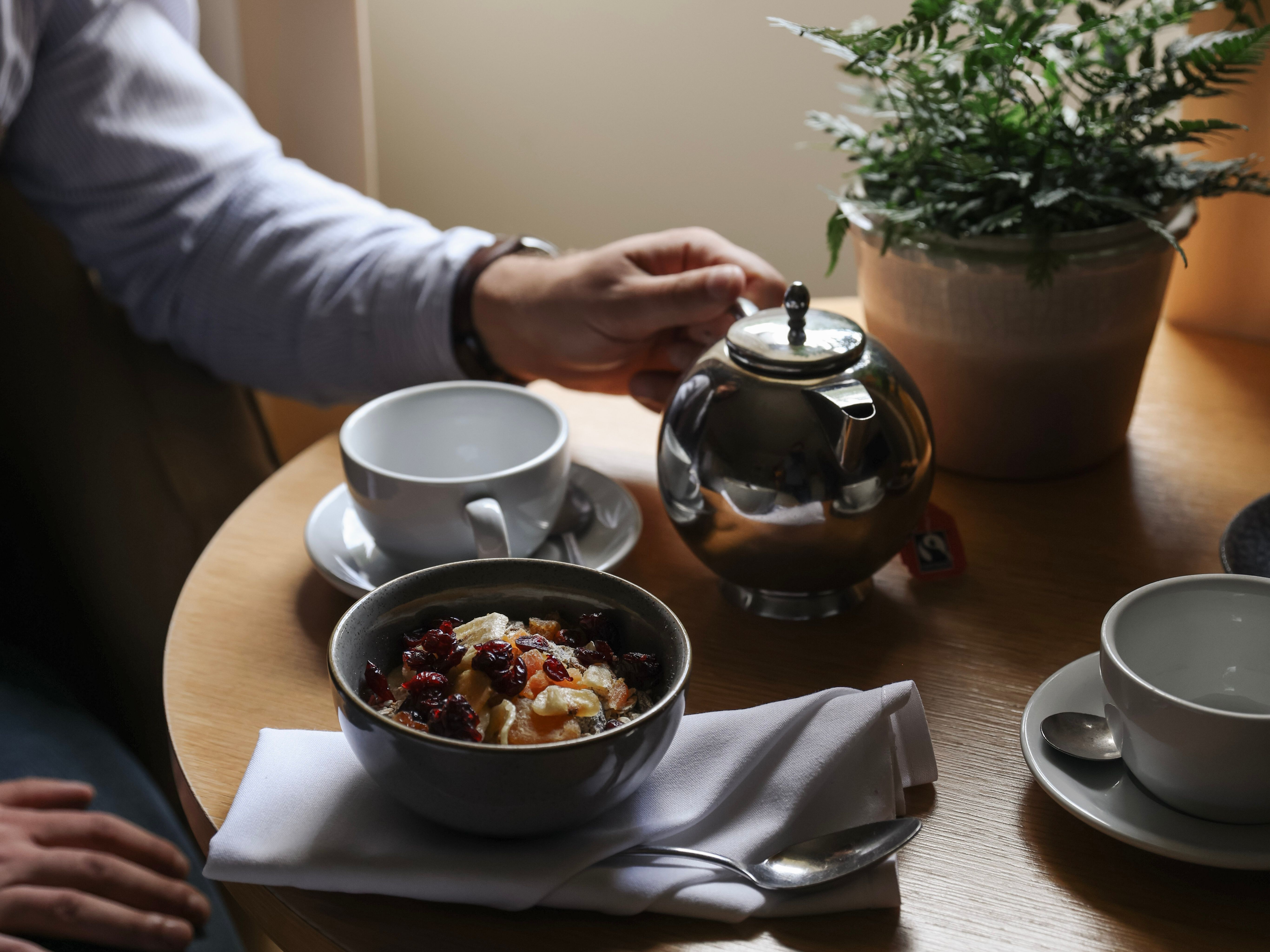 Person having breakfast with tea and oatmeal at a table by the window