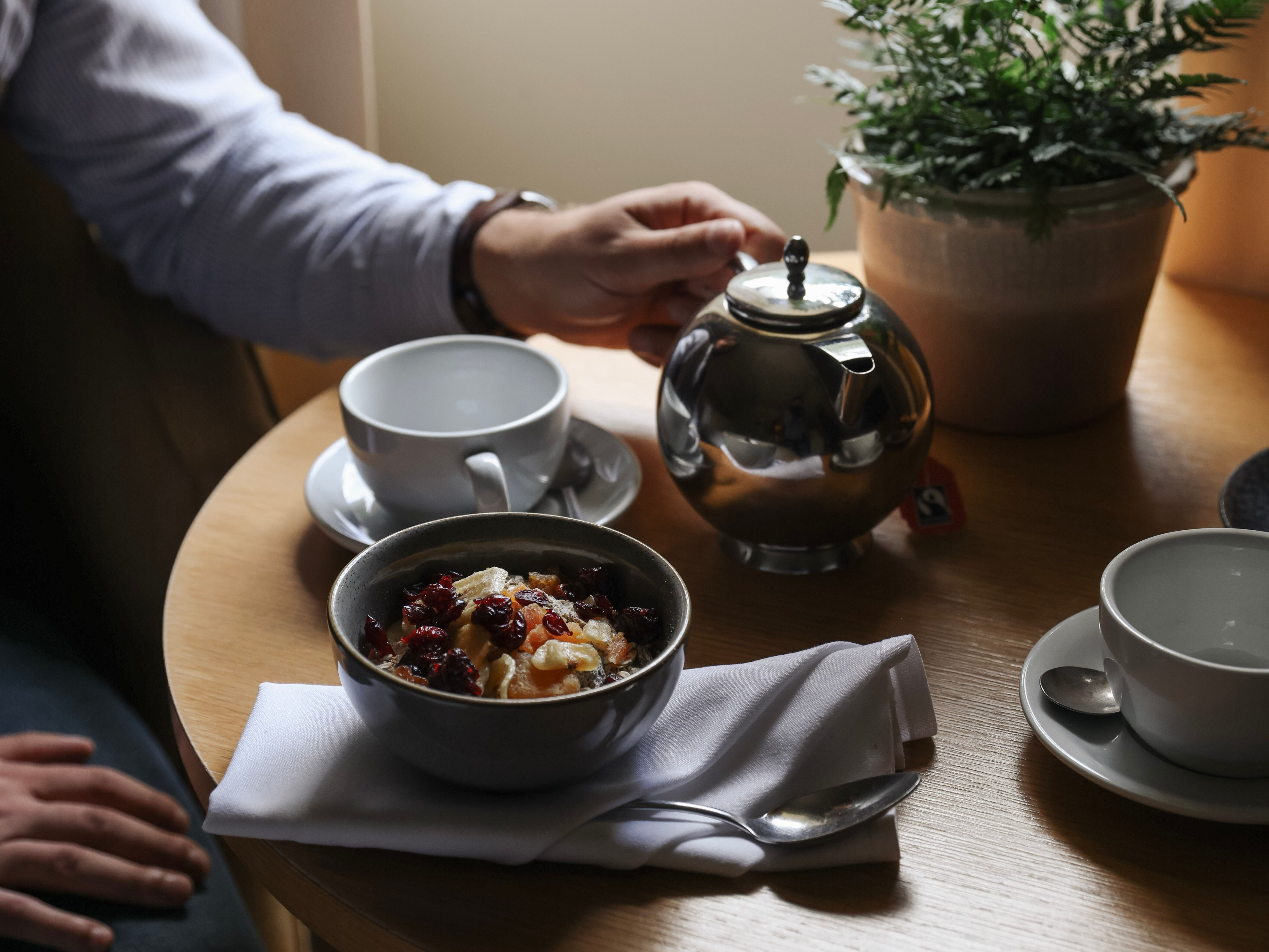Person having breakfast with tea and oatmeal at a table by the window