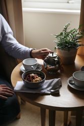 Person having breakfast with tea and oatmeal at a table by the window