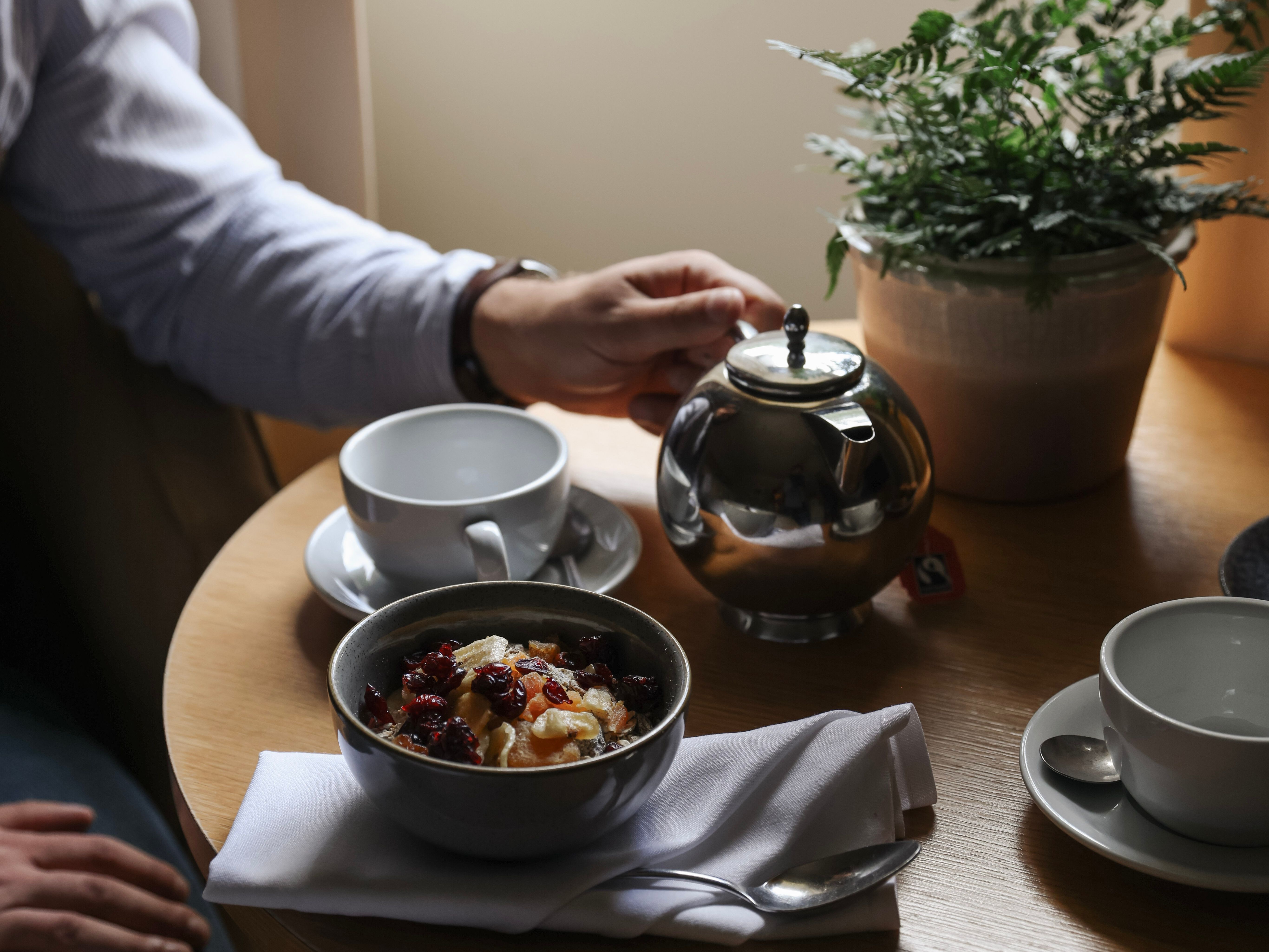 Person having breakfast with tea and oatmeal at a table by the window