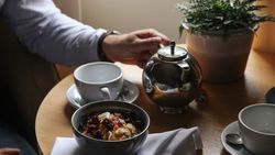 Person having breakfast with tea and oatmeal at a table by the window