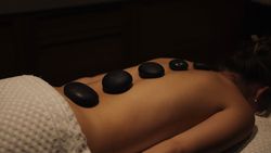 Person receiving a hot stone massage with stones placed on their back