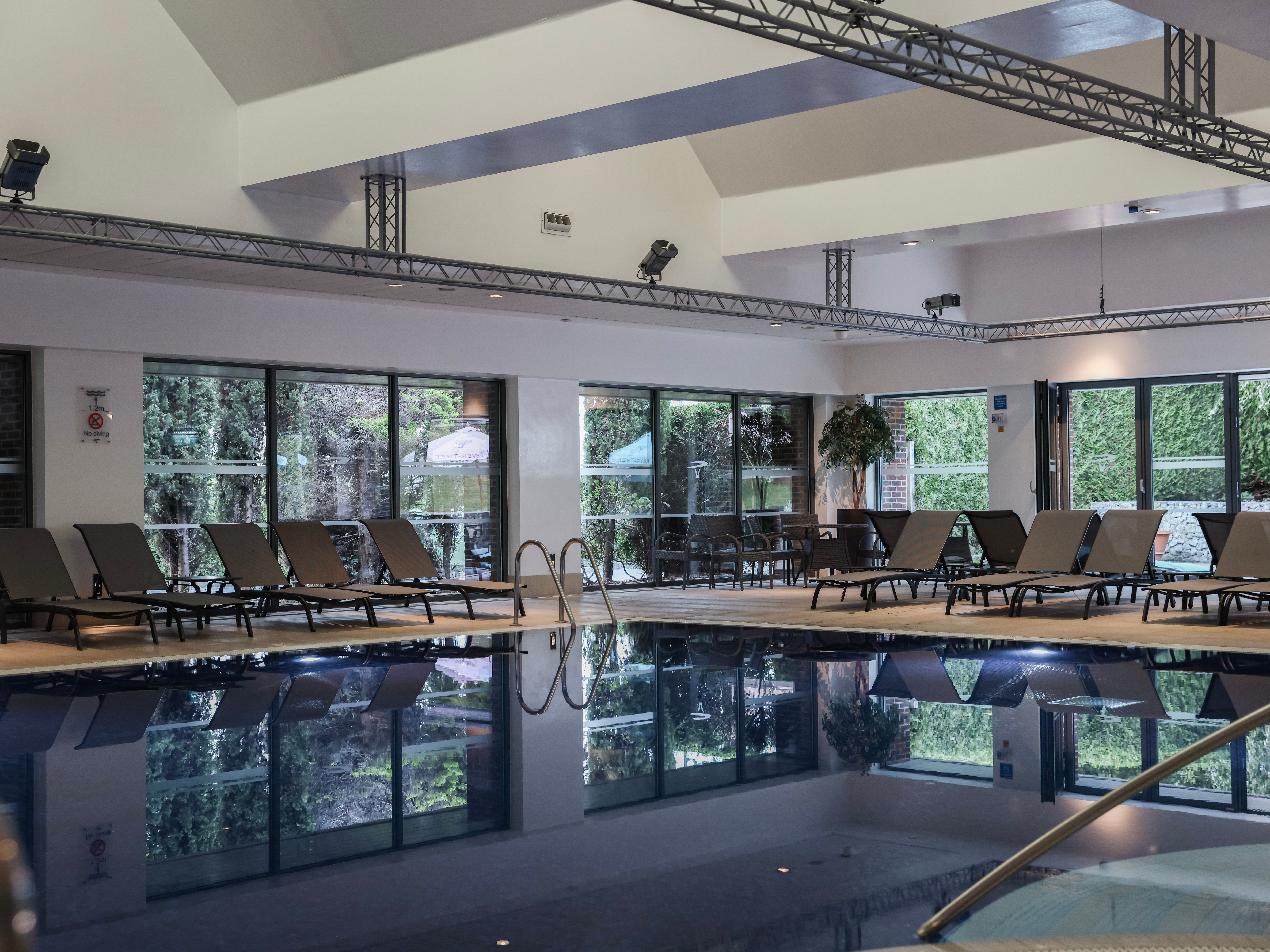 Indoor swimming pool area with lounge chairs and large windows