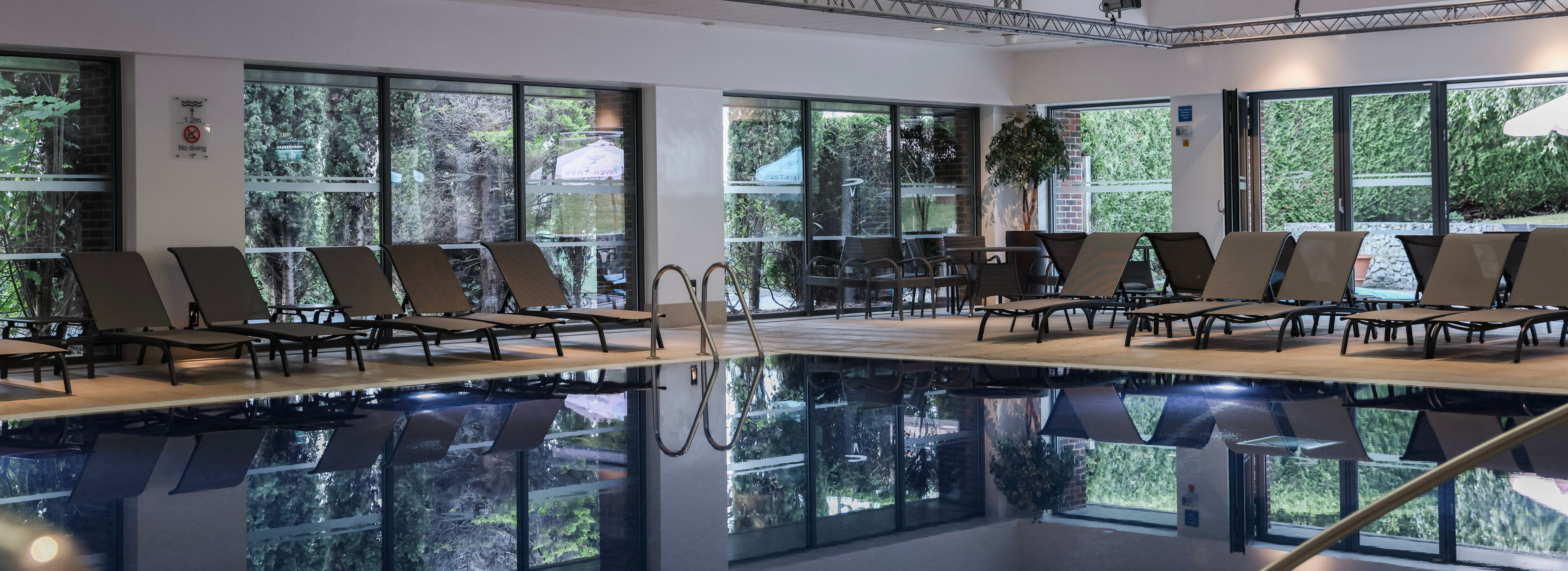 Indoor swimming pool area with lounge chairs and large windows