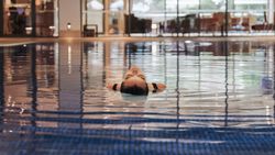 Person floating on their back in an indoor swimming pool