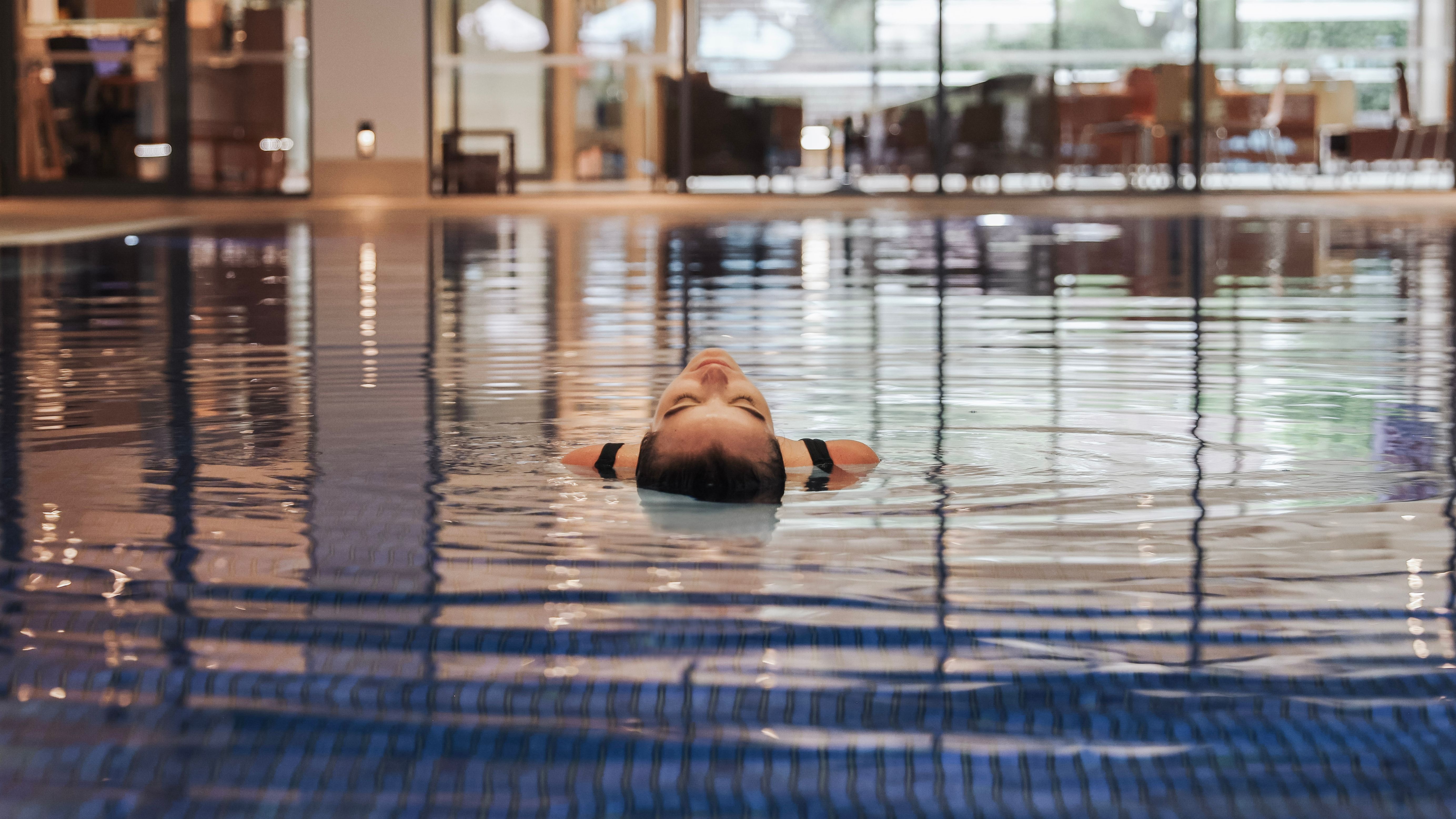 Person floating on their back in an indoor swimming pool