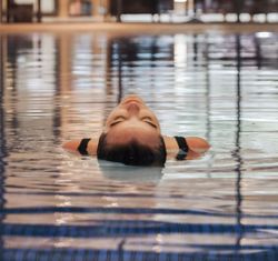 Person floating on their back in an indoor swimming pool