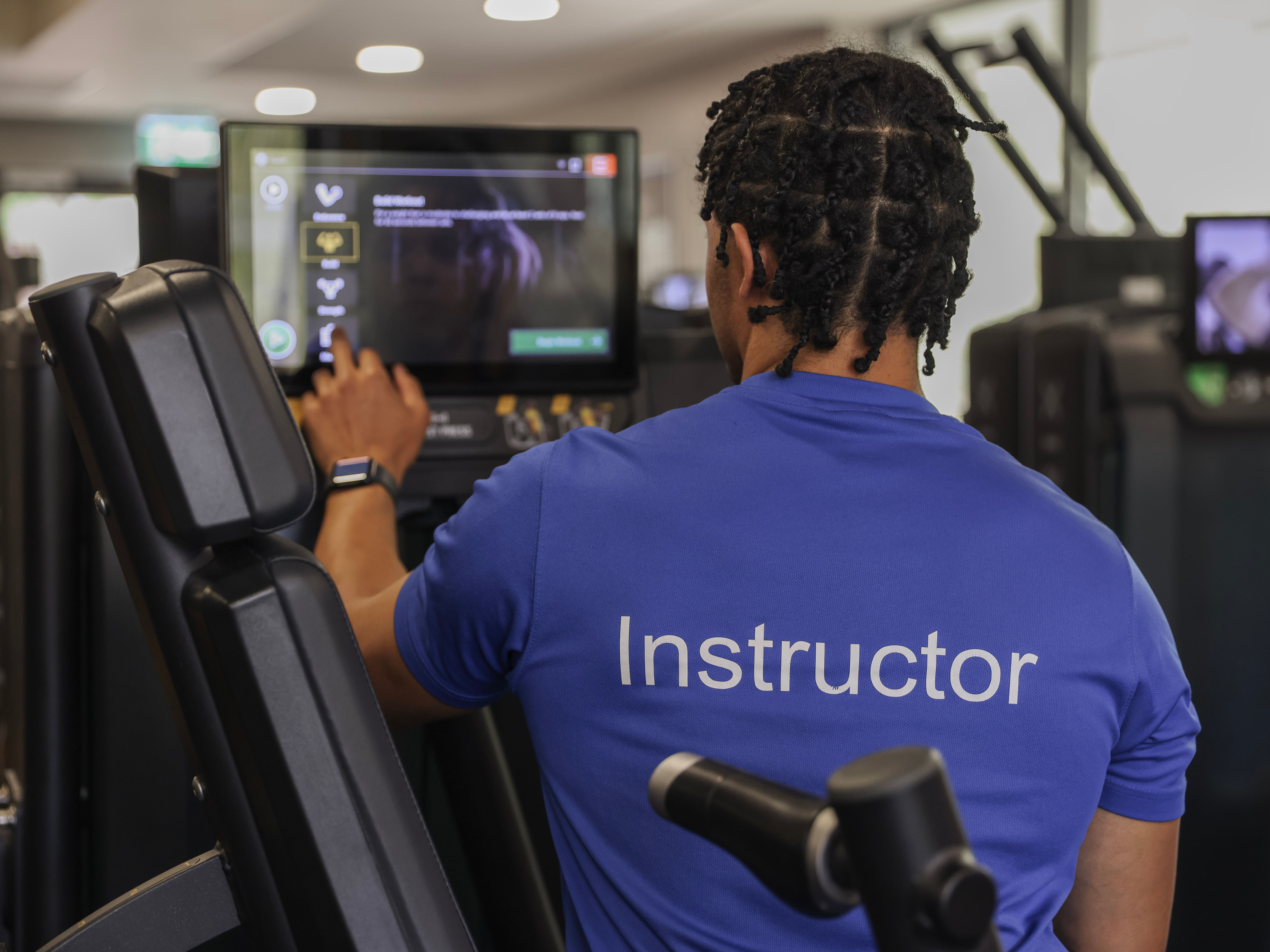 Fitness instructor using a touchscreen interface on gym equipment