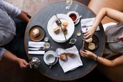 Table set for afternoon tea with pastries, scones, and tea, seen from above