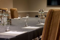 Conference table set with notepads, pens, glasses, and bottled water